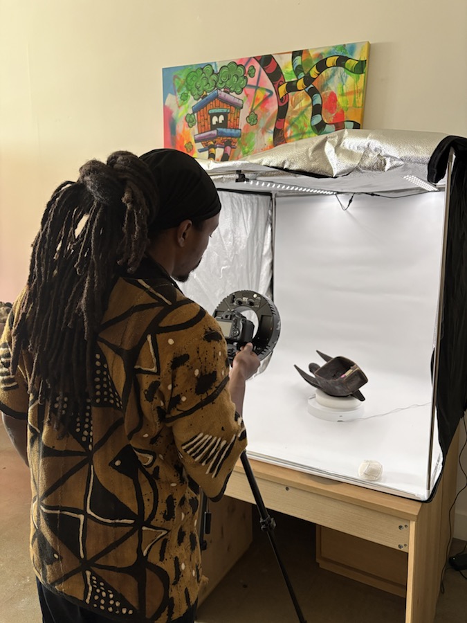 A photographer documents an object inside a light tent for the Leimert Park Digital Archive.